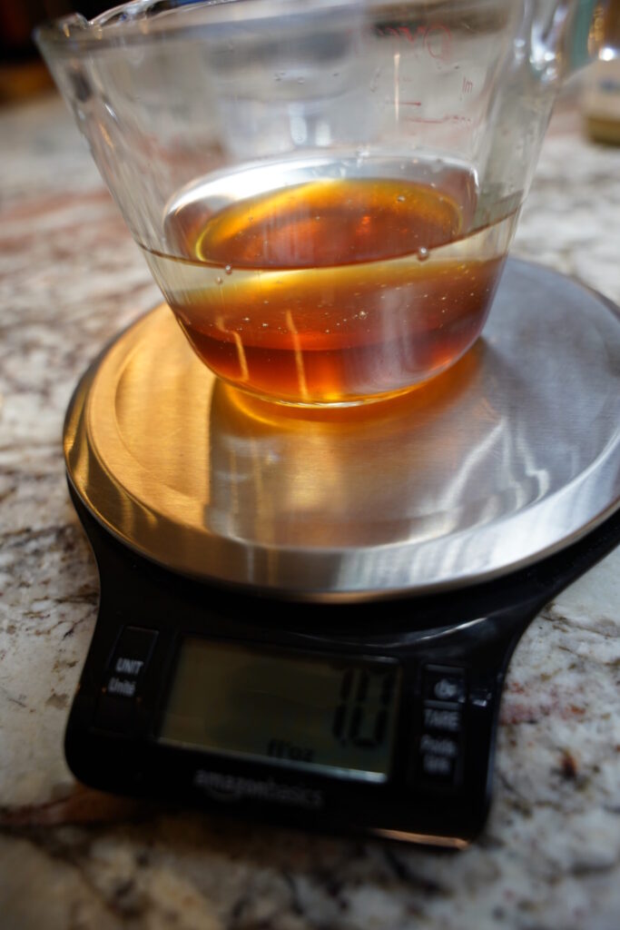 Equal parts honey and water in a microwave safe container on a scale.