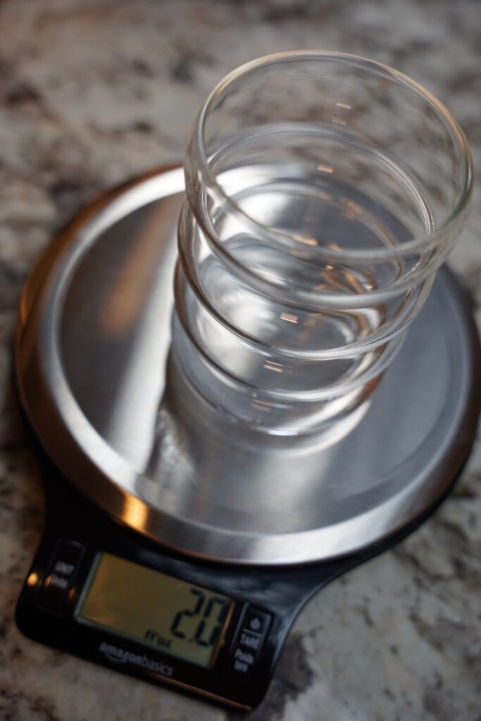 2 ounces of gin measured in a glass cup of scale.