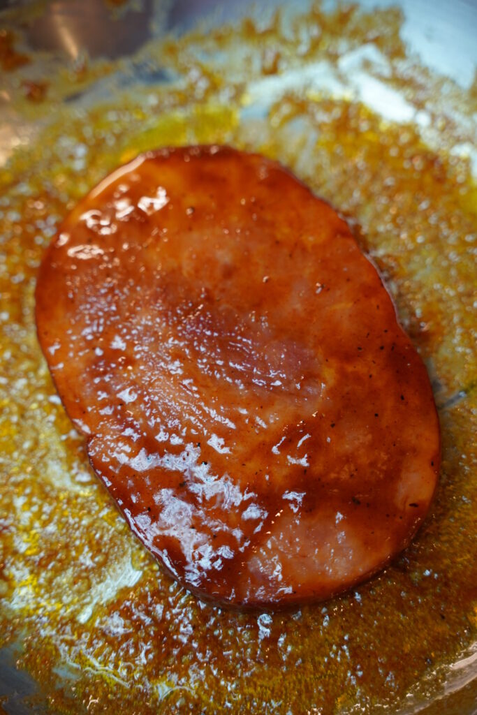 brown sugar dijon glazed ham, caramelized and looking beautiful in a stainless steel pan.