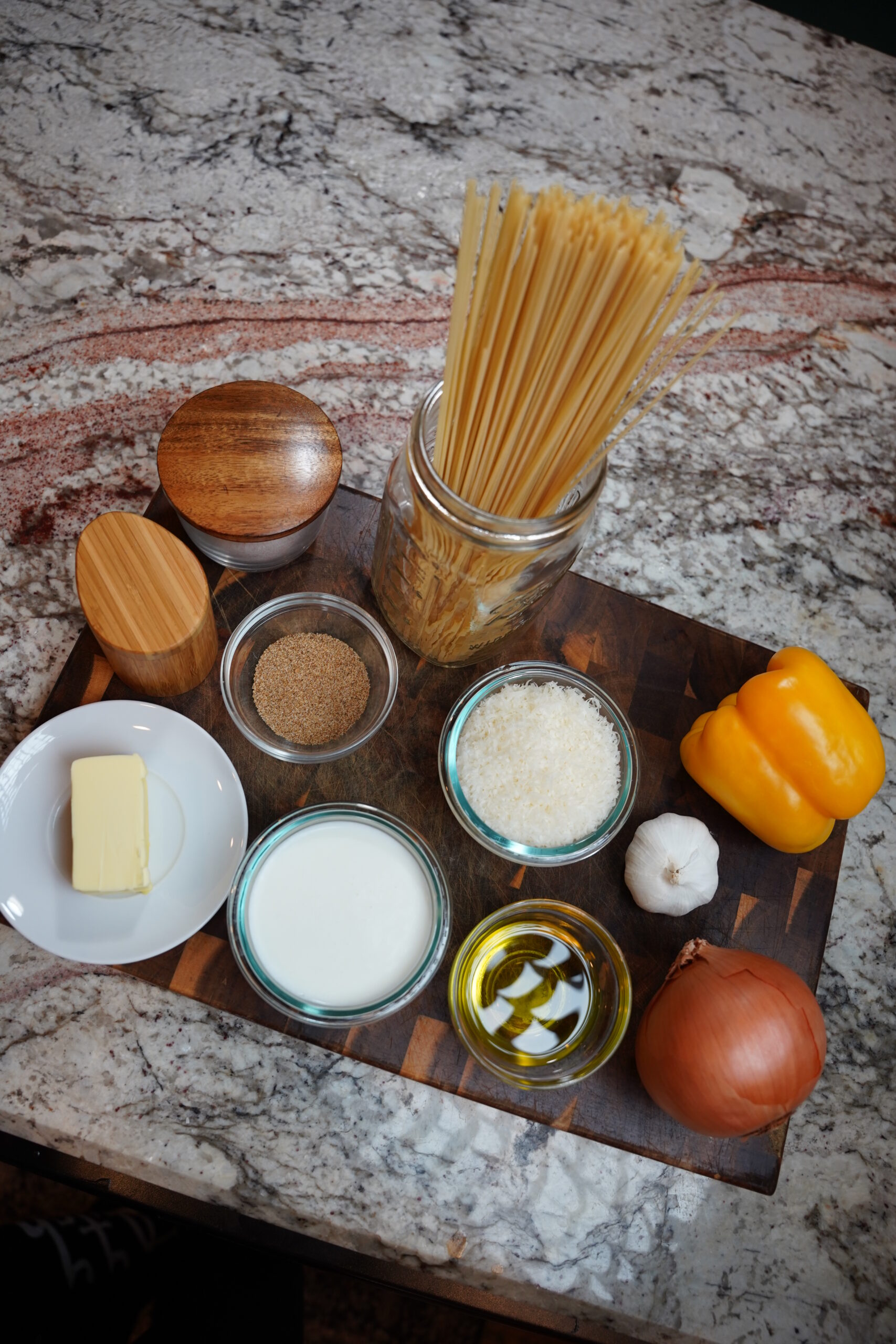 Cajun Shrimp Pasta ingredients. Spaghetti pasta noodles, yellow onion, yellow bell pepper, garlic, olive oil, parmesan, milk, butter, cajun seasoning, chili powder, paprika, chipotle smoked jalapeño powder (sub with smoked paprika) salt, pepper, butter. (Not pictured: Muir glen fire roasted tomatoes with green chili, and cream cheese)