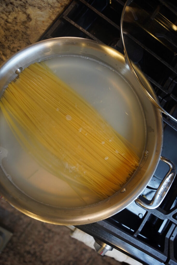 Cajun Shrimp Pasta Step 2. Spaghetti pasta noodles boiling in a large all clad stainless steel pan.