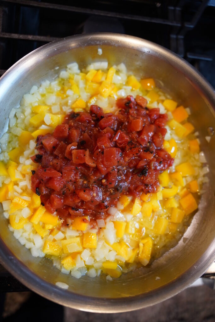Cajun Shrimp Pasta Step 4. Butter melted, onion softened, garlic, and bell pepper with Muir Glen Fire Roasted Tomato with green chili on top - in a large all clad stainless steel pan.
