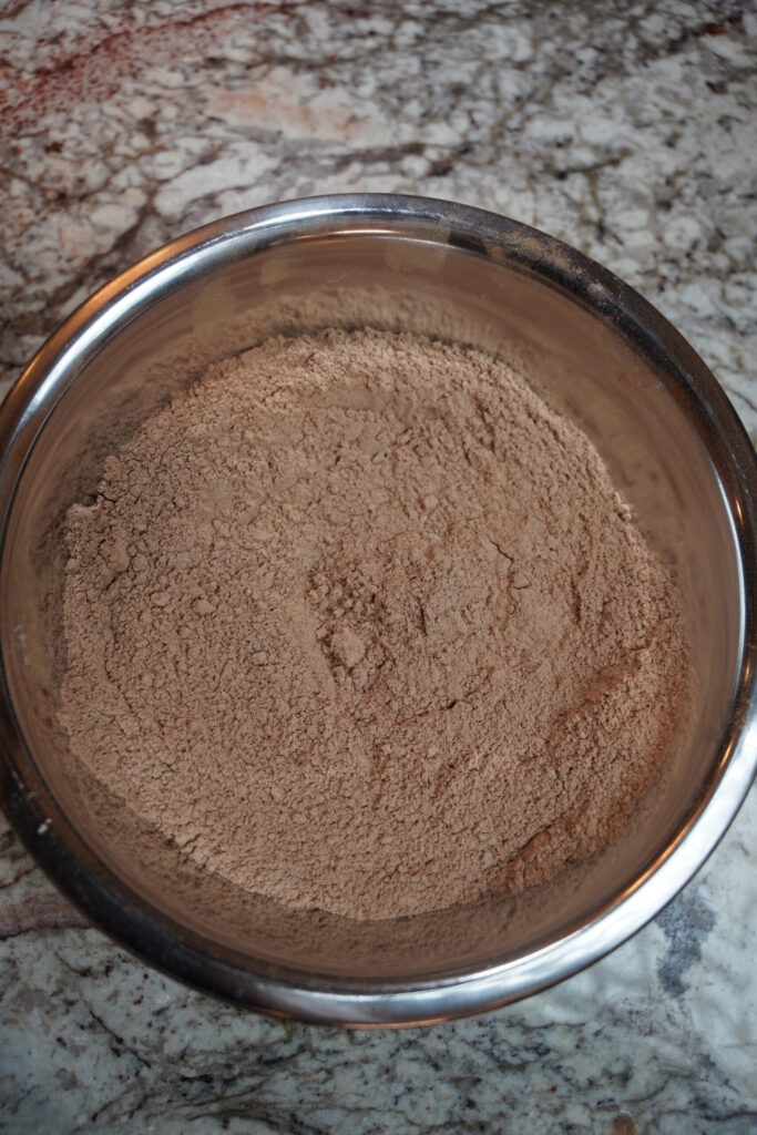 Flour, coco powder, baking powder and salt whisked for double chocolate macadamia nut cookies. Dry ingredients.