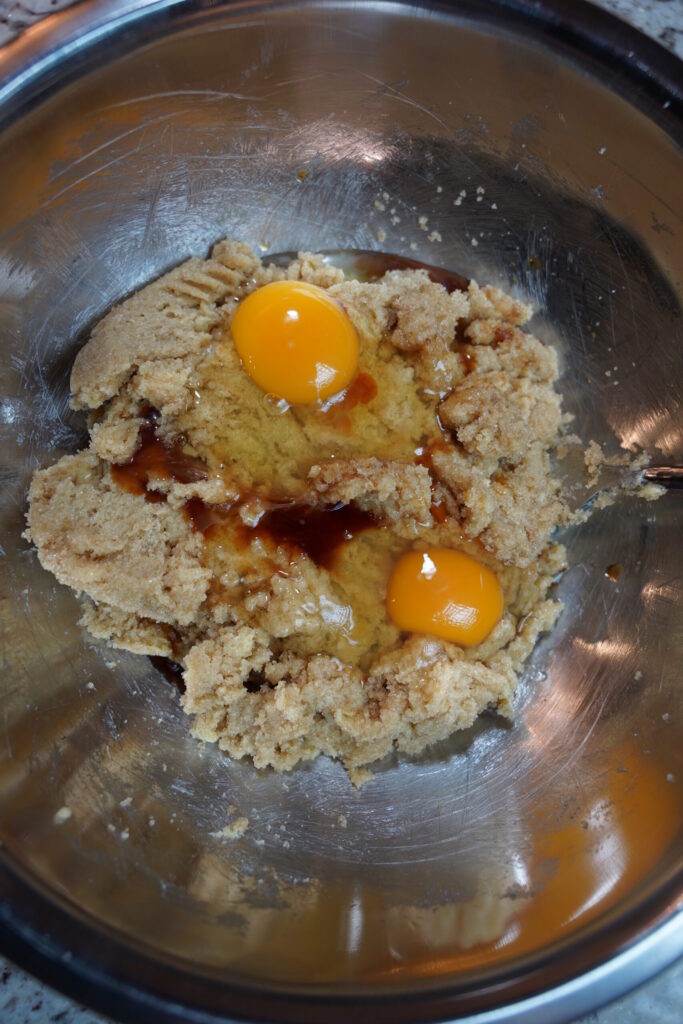 Vanilla and egg added to creamed butter and sugar for double chocolate macadamia nut cookies