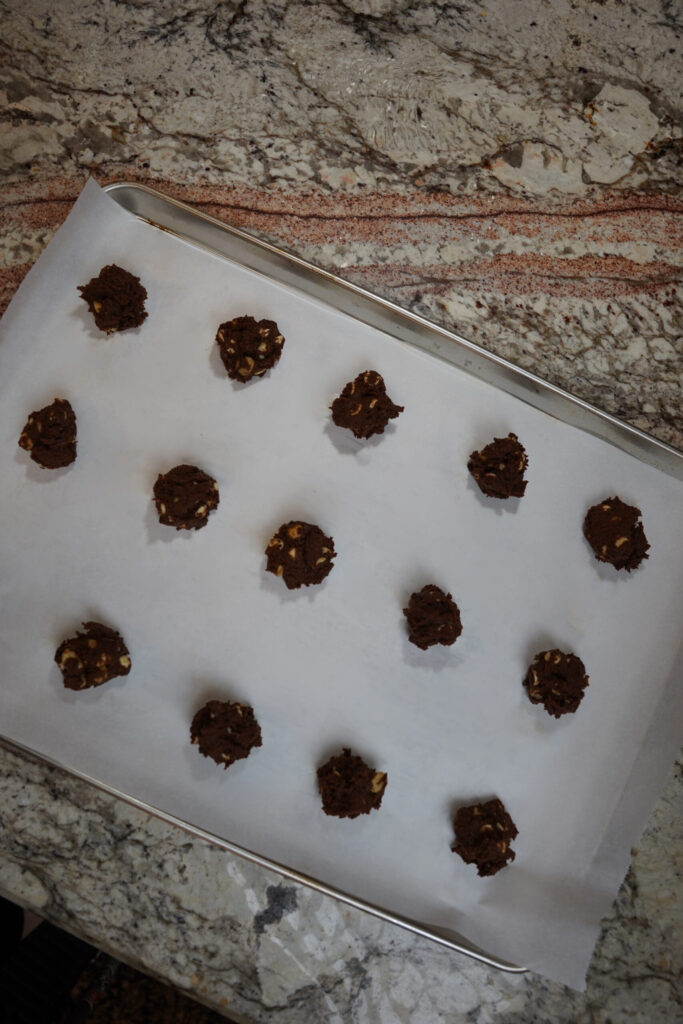 Double Chocolate Macadamia Nut Cookie dough balls sitting on a cookie sheet with parchment paper.