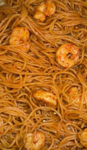 Close up of glossy spaghetti noodles with a gochujang sauce and korean shrimp scampi.