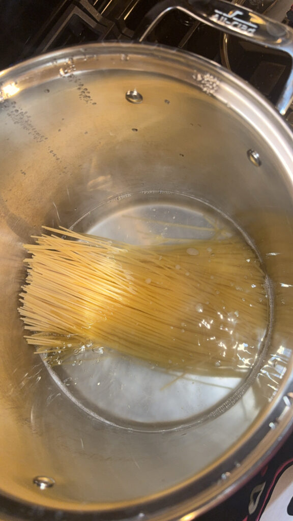 1 lb of spaghetti noodles boiling in a large pot.