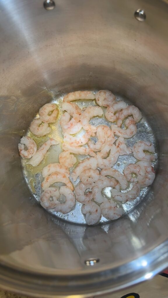 Shrimp cooking in garlic, butter, and olive oil. Has a sprinkle of salt and pepper