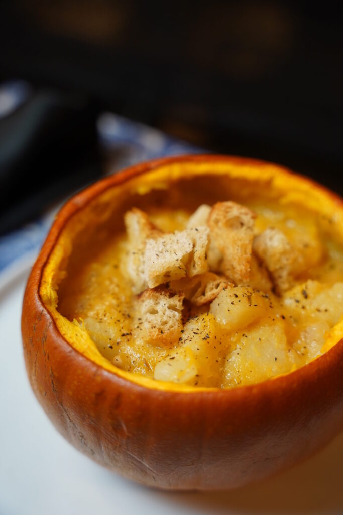 Potato and pumpkin soup served in a pumpkin pie pumpkin, with rosemary croutons and black pepper sprinkles over the top