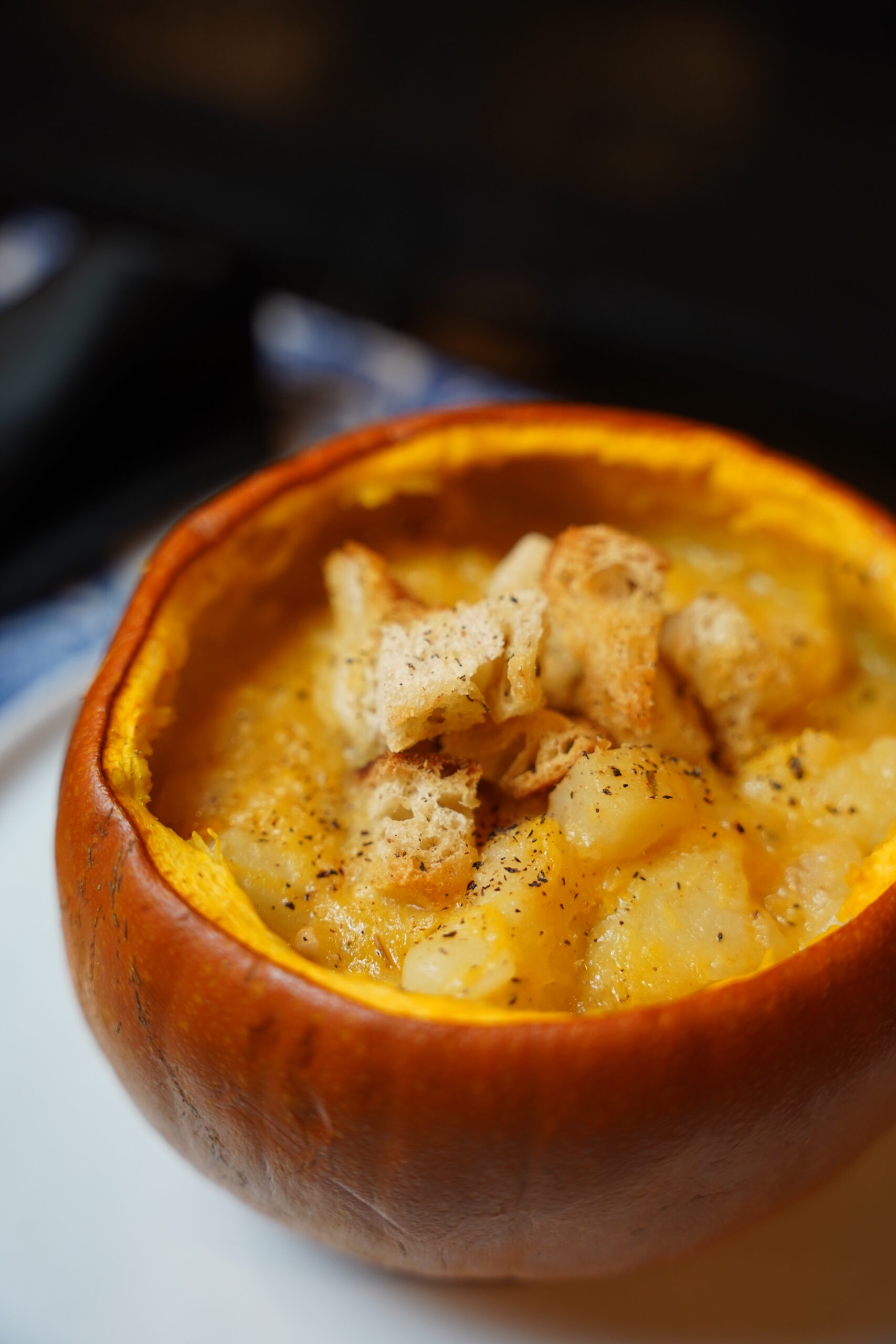 Potato and pumpkin soup served in a pumpkin pie pumpkin, with rosemary croutons and black pepper sprinkles over the top