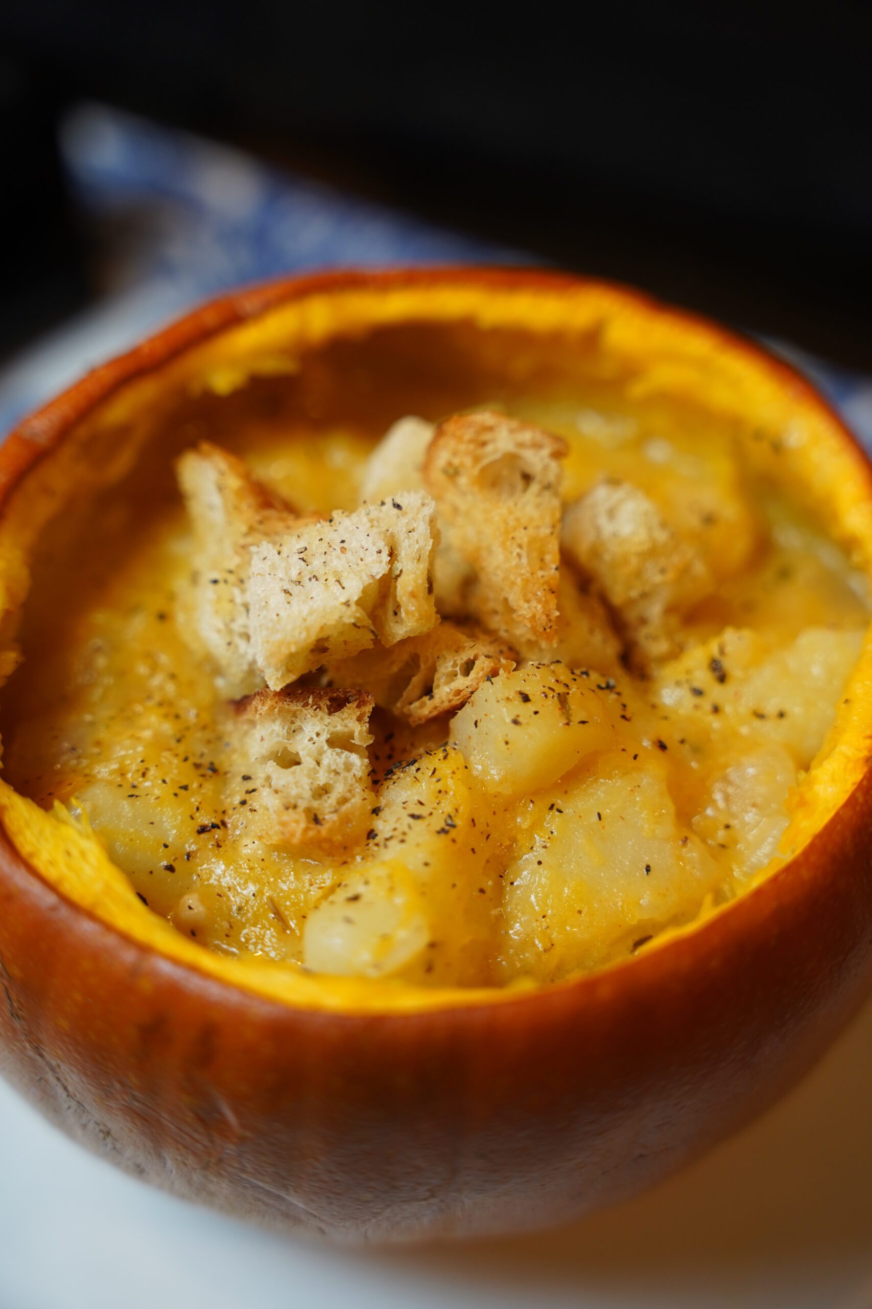 Potato and pumpkin soup served in a pumpkin pie pumpkin, with rosemary croutons and black pepper sprinkles over the top