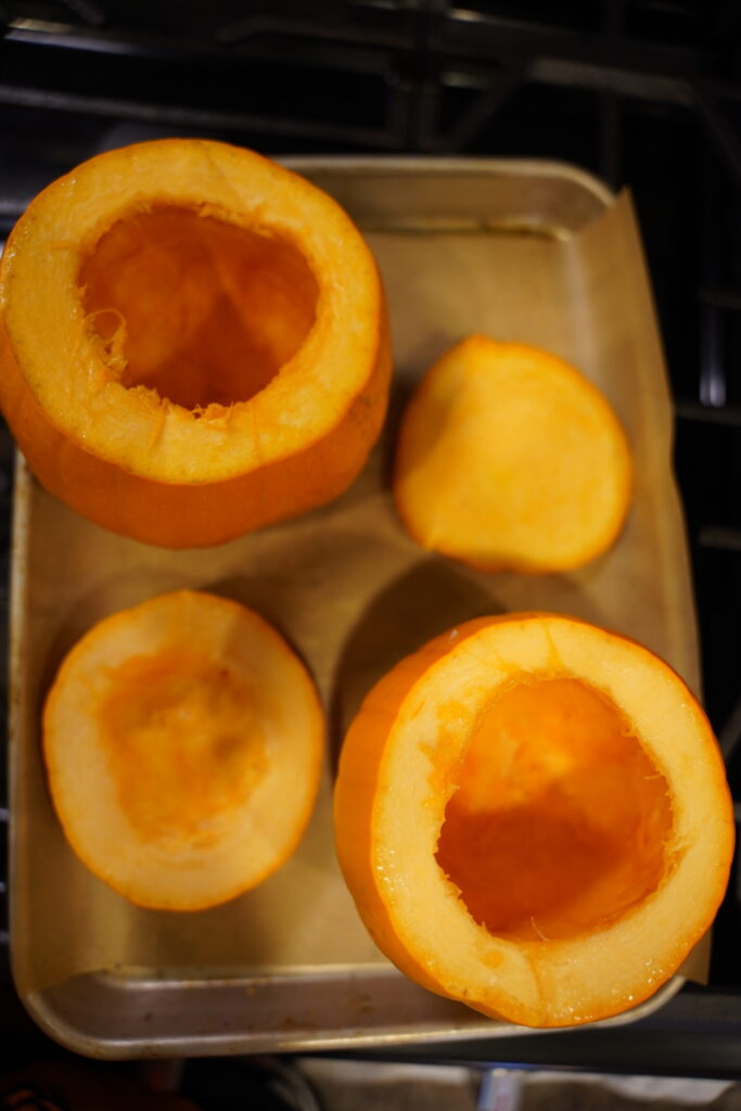 pumpkins on a sheet pan with tops cut off, seeds and strings removed. Ready for roasting.