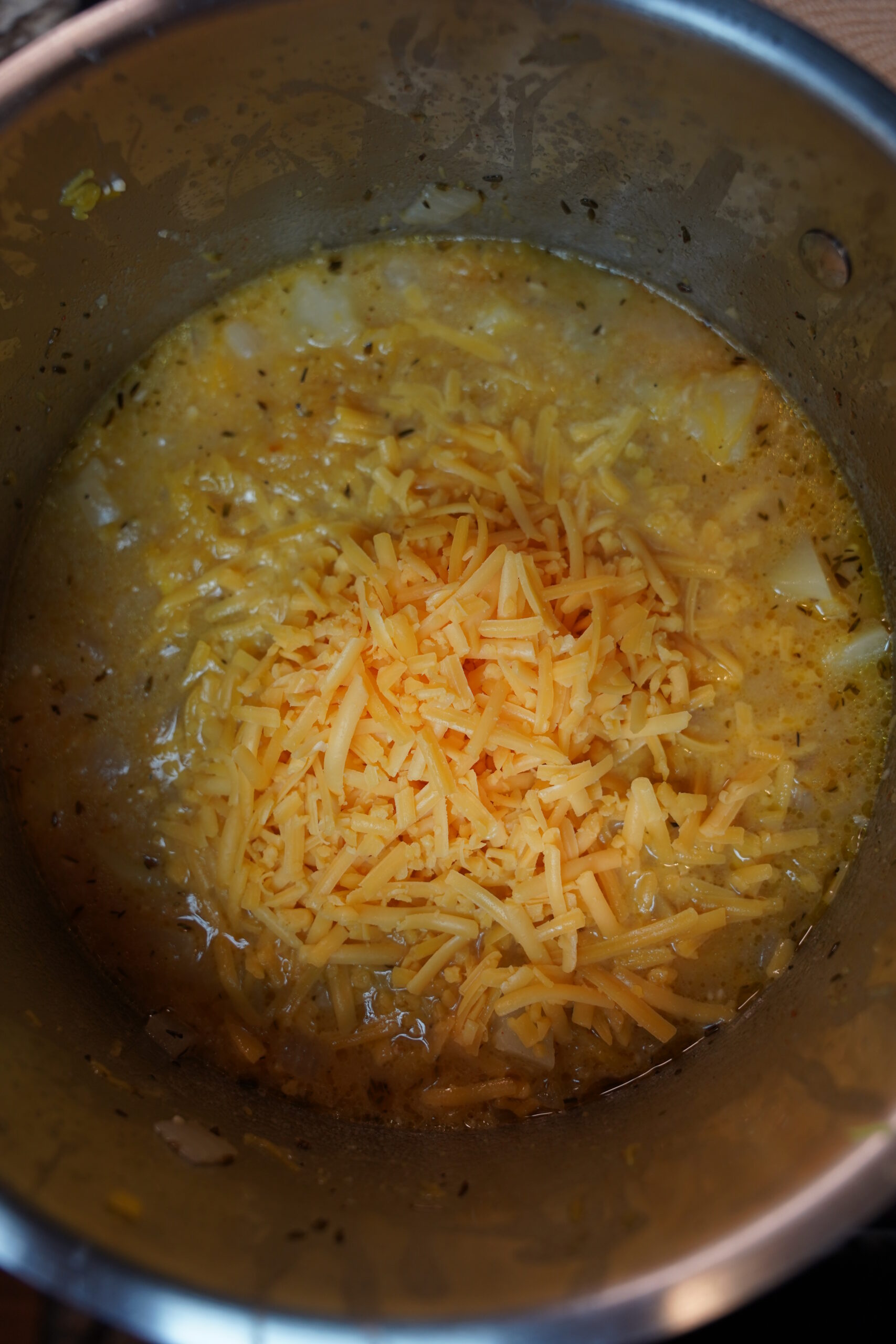 Pumpkin scooped into soup and cheddar cheese added to the top.