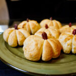 Delicious pumpkin shaped dinner rolls on a green plate. Warm, golden bread recipe.