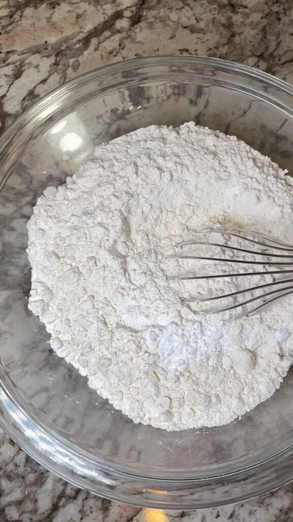 Flour, baking soda, and salt with a whisk inside. Dry ingredients for snickerdoodles cookies.