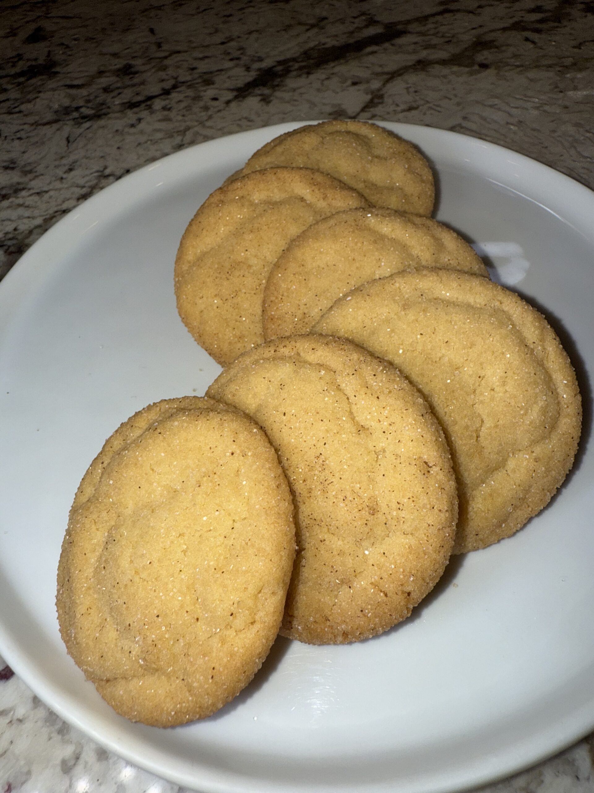 A line of 6 Completed Snickerdoodle Cookies, perfectly baked and artistically sitting on a plate