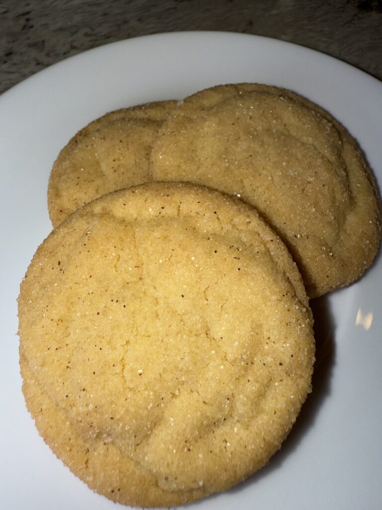 3 Completed Snickerdoodle Cookies, perfectly baked and sitting on a plate.