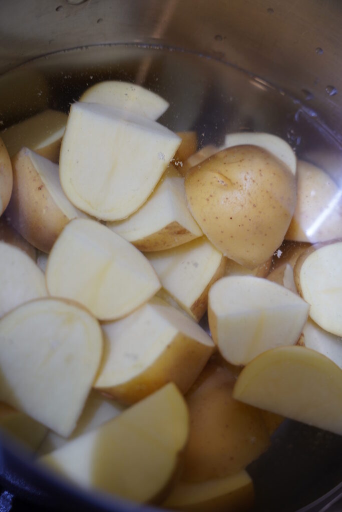 yukon gold potatoes cut into quarters and boiling in a pot