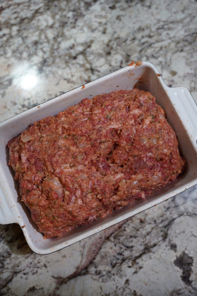 Meatloaf shaped in a pan before baking.