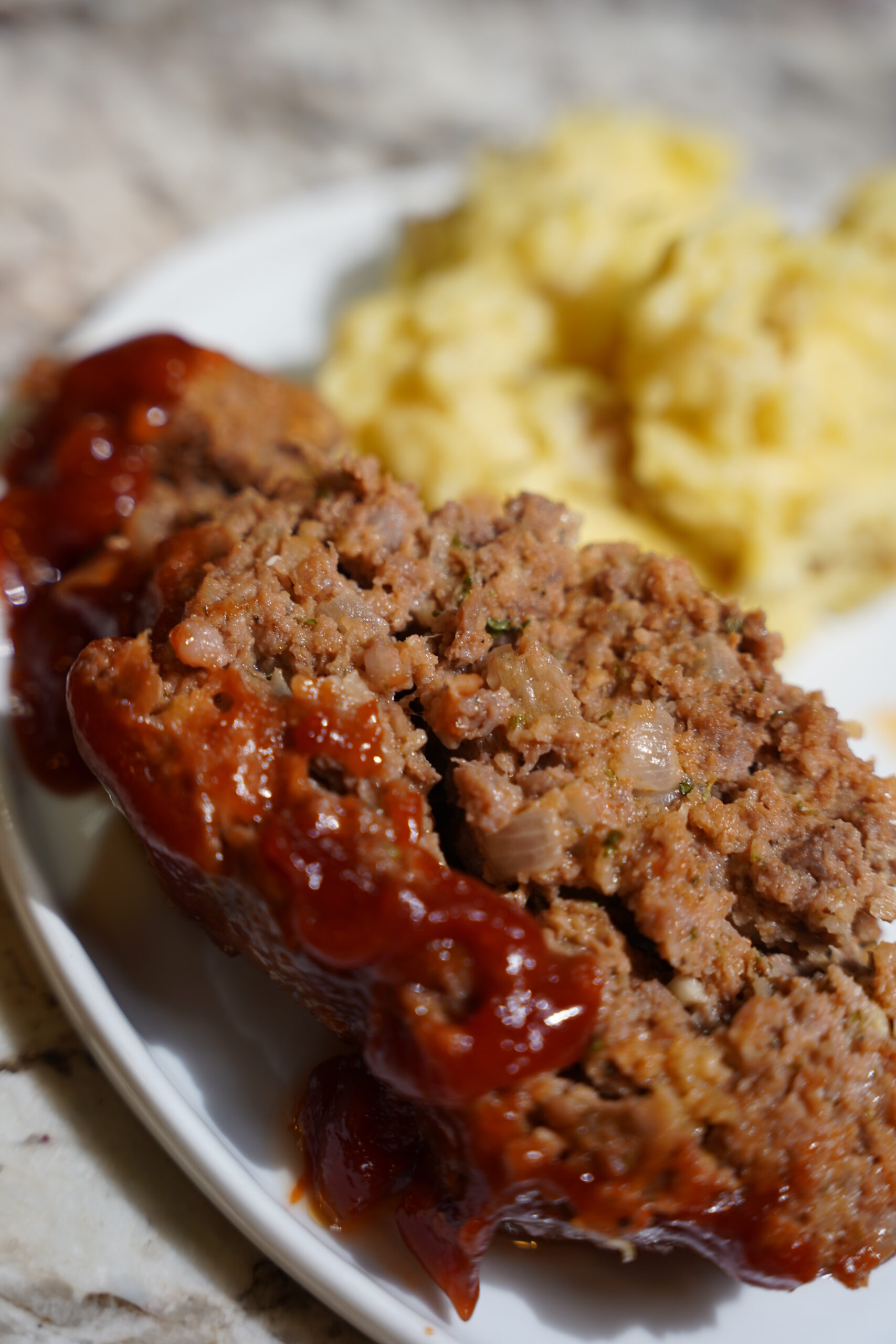 Meatloaf and Brown Butter Mashed Potatoes on a white plate sitting on a granite countertop