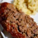 Meatloaf and Brown Butter Mashed Potatoes on a white plate sitting on a granite countertop