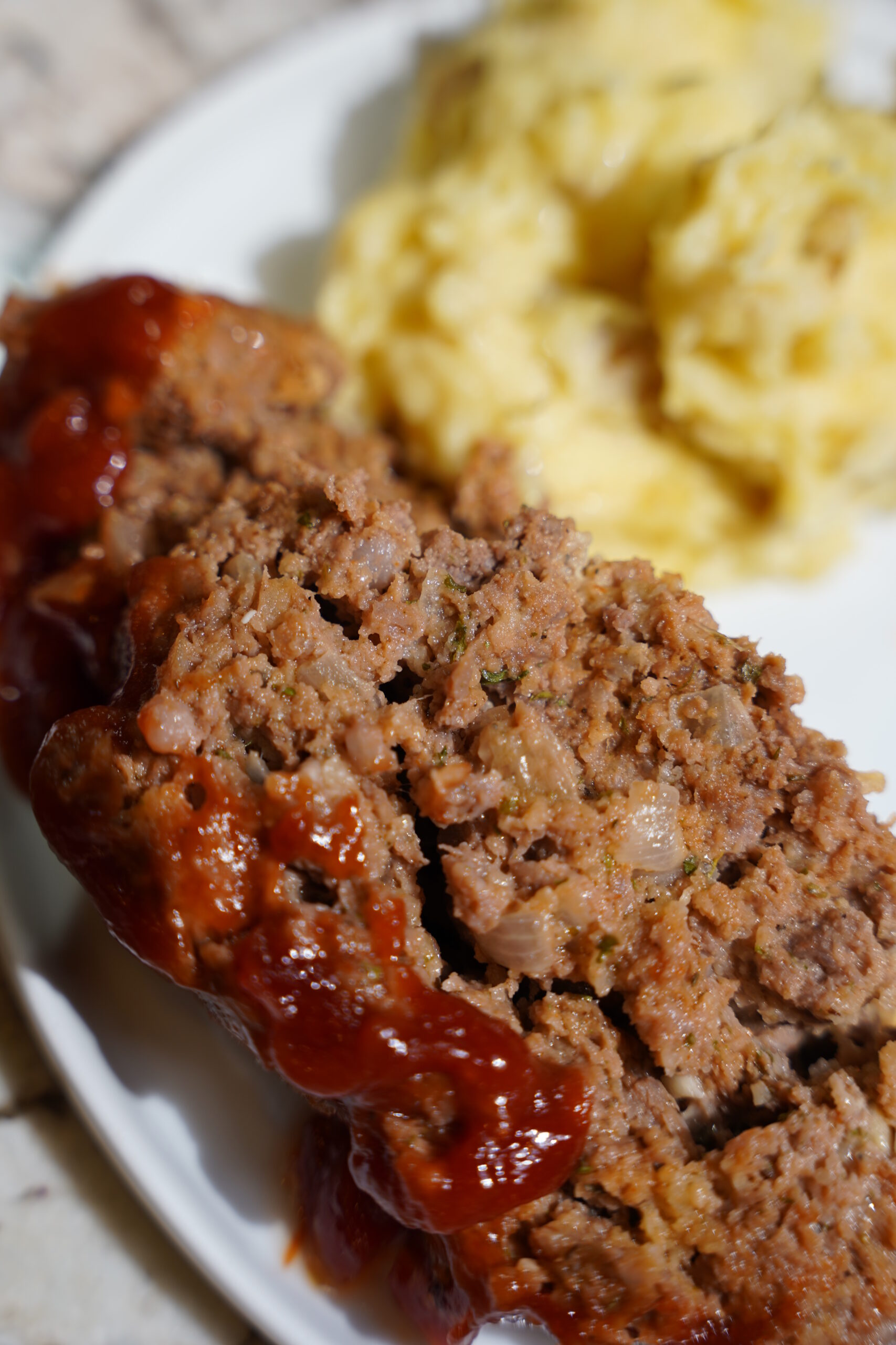 Meatloaf and Brown Butter Mashed Potatoes on a white plate sitting on a granite countertop