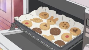 anime cookies with cute shapes on a cookie sheet going into an oven.