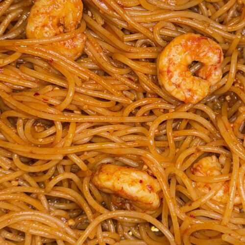 Close up of glossy spaghetti noodles with a gochujang sauce and korean shrimp scampi.