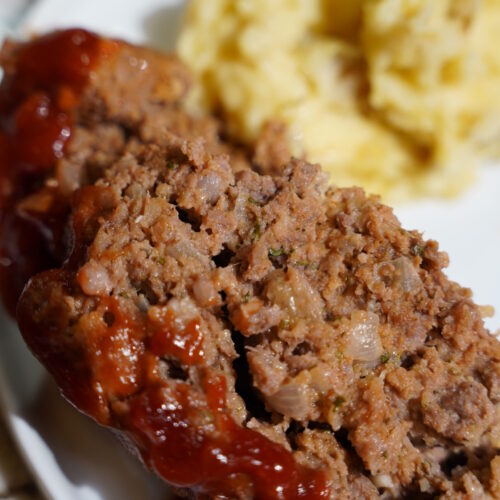 Meatloaf and Brown Butter Mashed Potatoes on a white plate sitting on a granite countertop