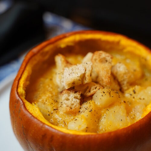 Potato and pumpkin soup served in a pumpkin pie pumpkin, with rosemary croutons and black pepper sprinkles over the top